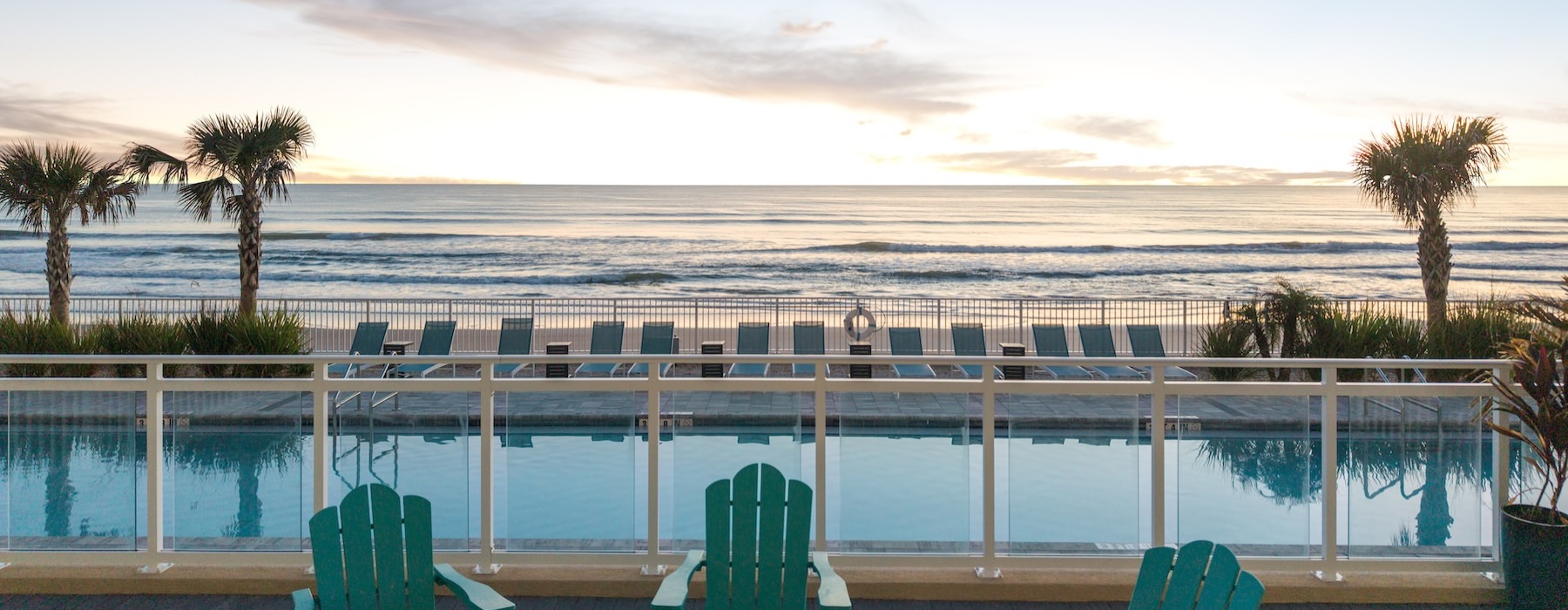 seating by a pool with an ocean and palm trees behind it